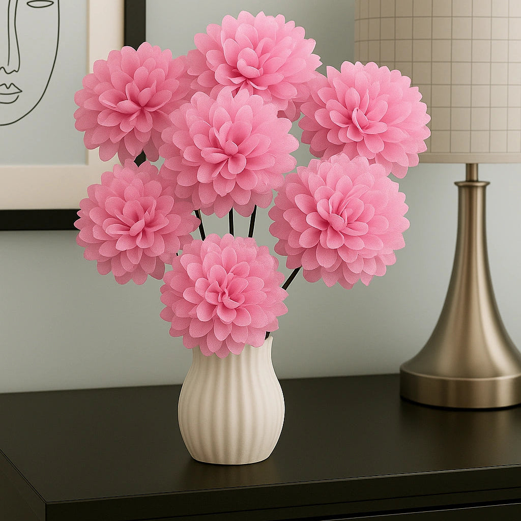 Pink flowers in a white vase on a dark surface with a lamp and framed picture in the background.