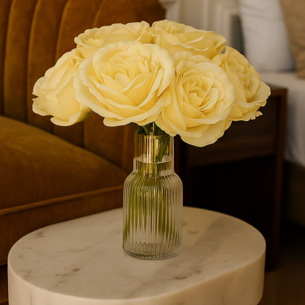 Bouquet of yellow roses in a clear vase on a marble table with a blurred background