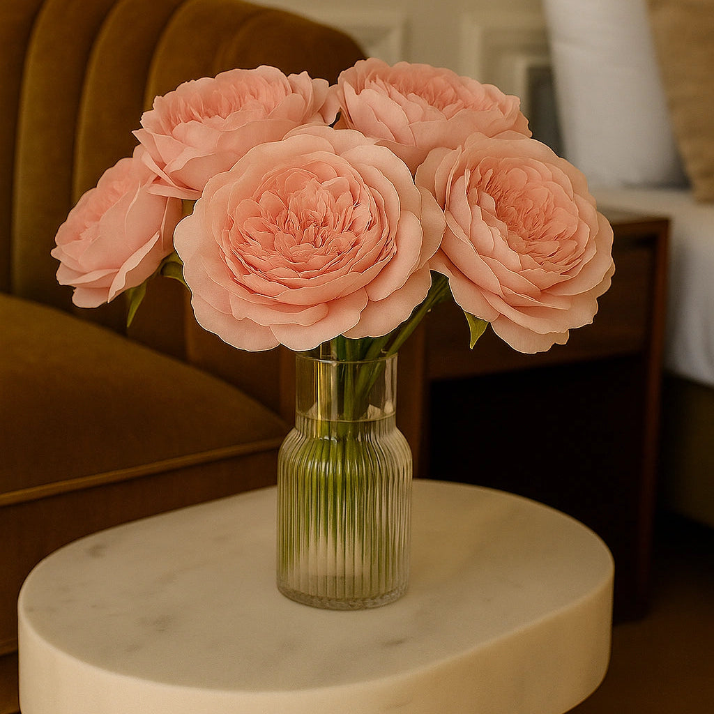 Bouquet of pink roses in a clear vase on a marble table with a blurred indoor background