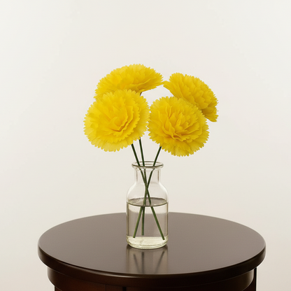 Clear vase with yellow flowers on a dark surface against a light background