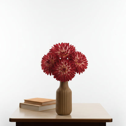 Red flowers in a vase on a table with a blurred background