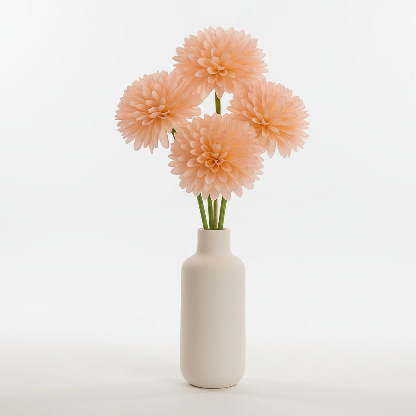 White vase with peach-colored flowers on a dark surface with decorative elements in the background