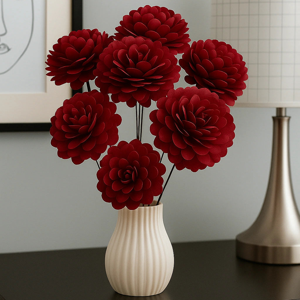 Red flowers in a white vase on a dark surface with a lamp and framed picture in the background.