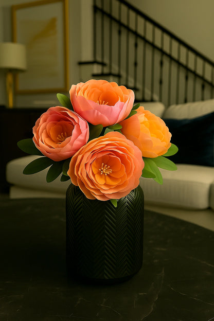 Bouquet of orange and pink flowers in a black vase on a dark surface with a blurred indoor background.