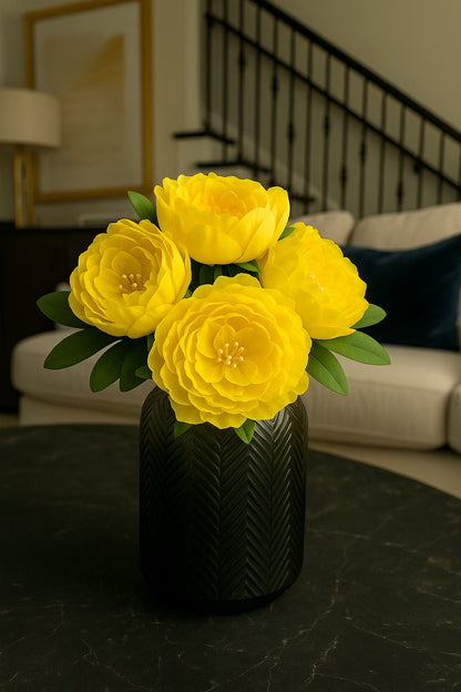 Yellow flowers in a black vase on a dark surface with a blurred indoor background