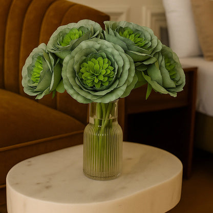 Green floral arrangement in a vase on a marble table with a blurred indoor setting.