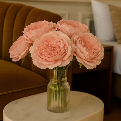 Bouquet of pink roses in a clear vase on a marble table with a blurred indoor background
