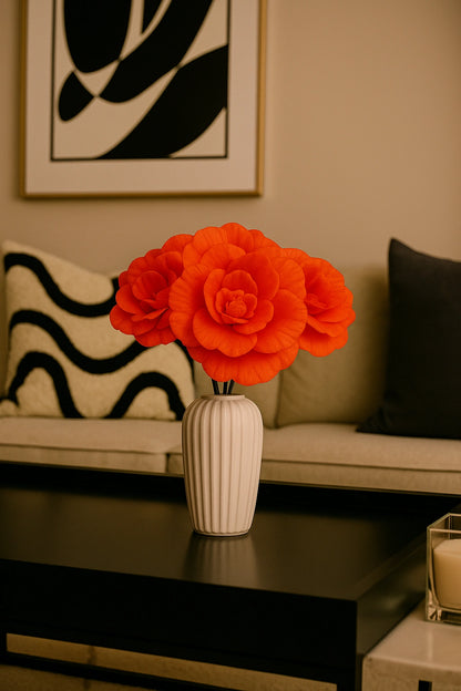 Orange flowers in a vase on a coffee table with a couch and abstract art in the background