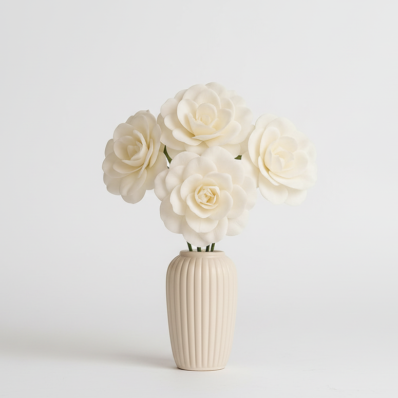 White ceramic vase with ribbed texture holding white flowers on a light gray background