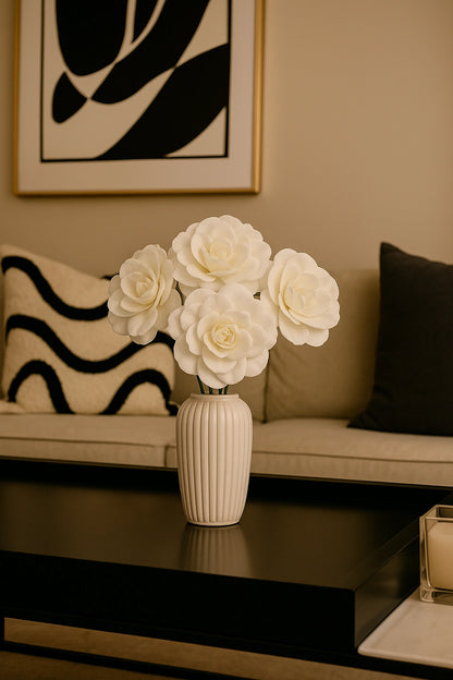 White flowers in a vase on a coffee table with a couch and abstract art in the background
