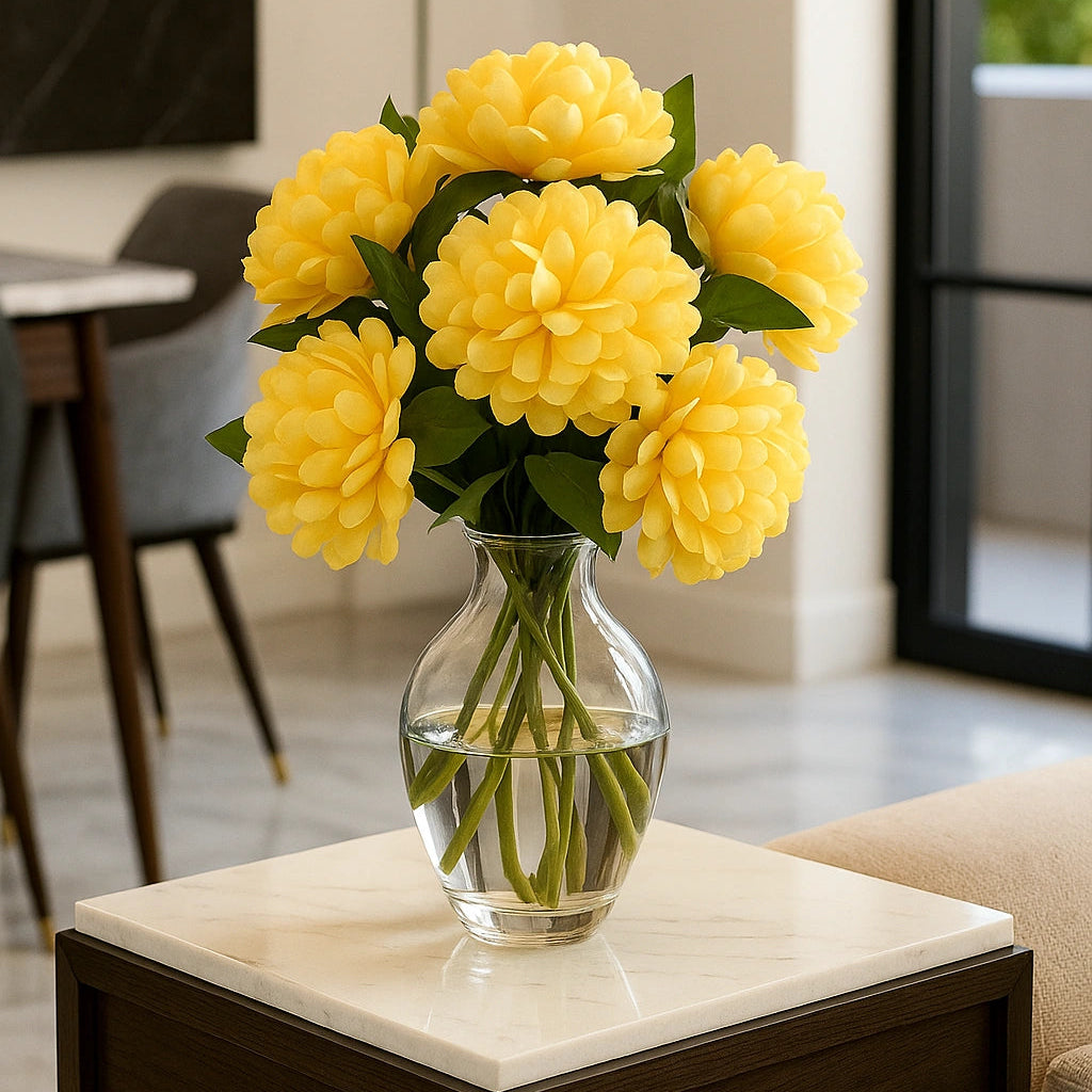 Yellow flowers in a clear vase on a marble table in a living room.