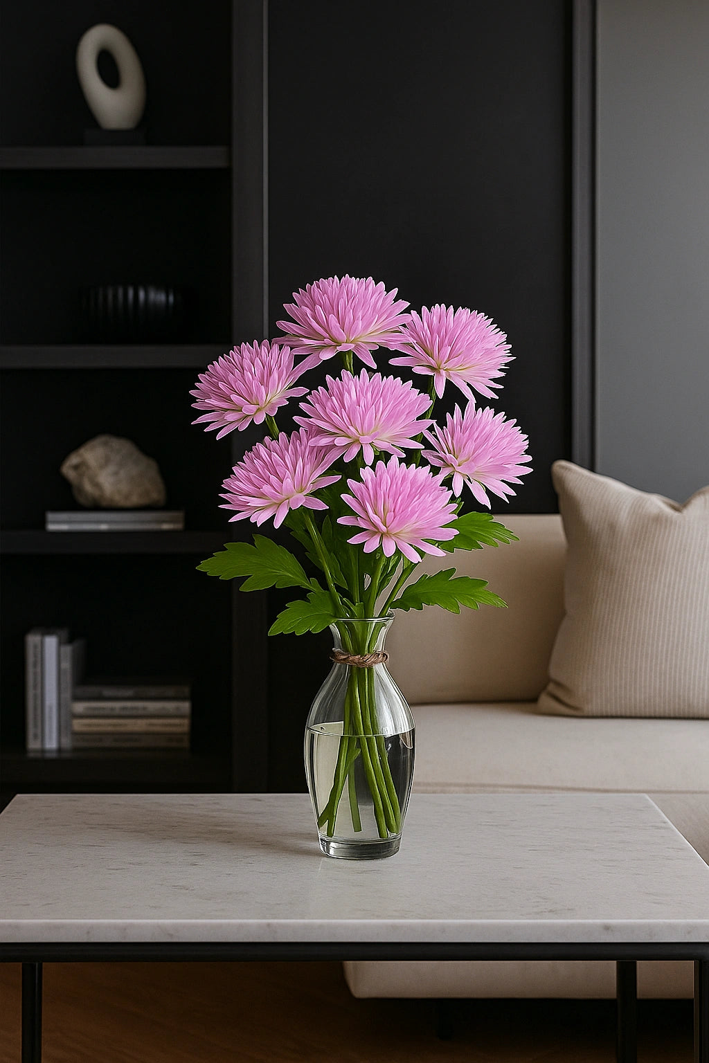 Pink flowers in a vase on a coffee table with a dark wall and beige sofa in the background