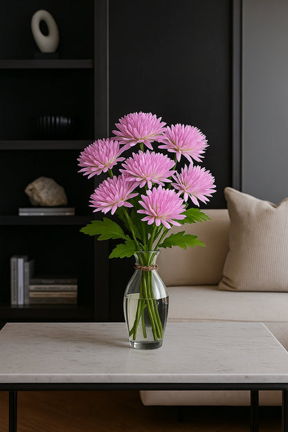 Pink flowers in a vase on a coffee table with a dark wall and beige sofa in the background