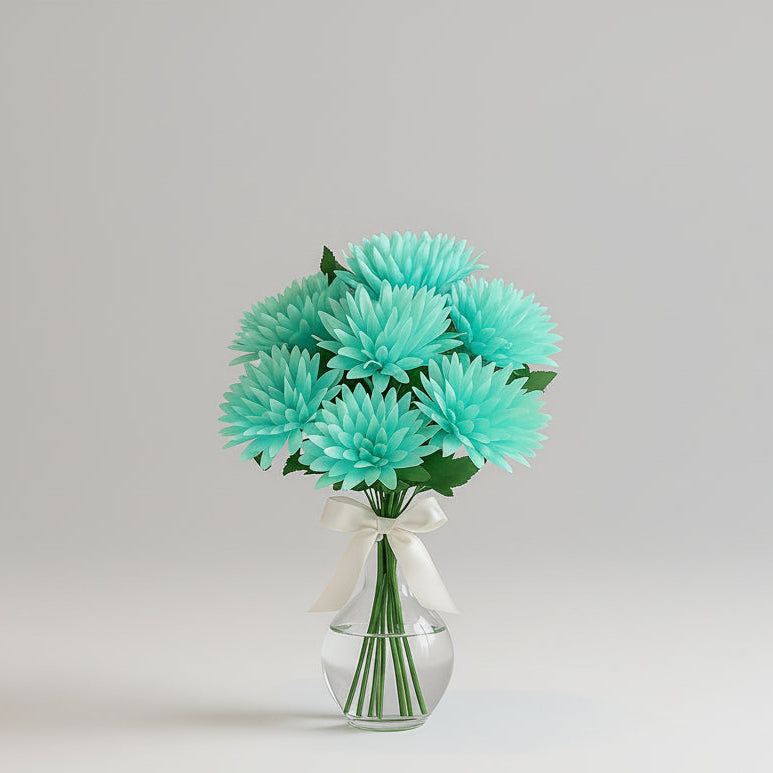 Turquoise flowers in a clear vase on a marble table with a neutral-colored sofa and window in the background.