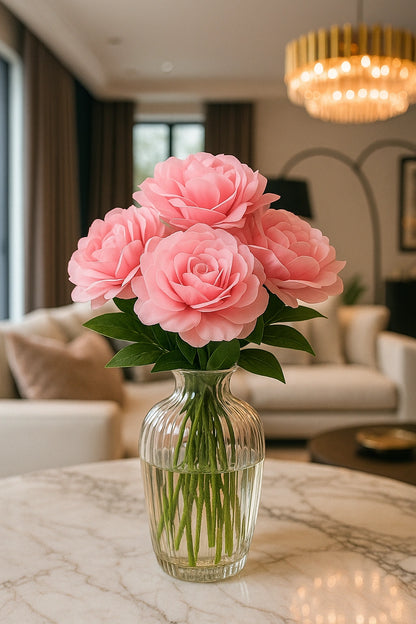 Pink roses in a clear vase on a marble table in a living room.