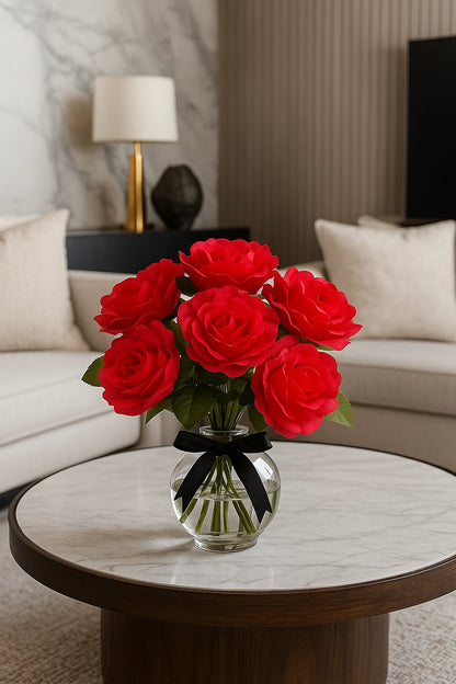 Bouquet of red roses in a clear vase with black ribbon on a marble table in a living room.